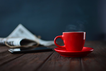 Morning cup of coffee. Warm coffee and morning news concept on a wooden textured table.