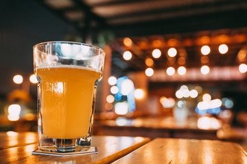 One pint of beer on restaurant table with copy space on blur bokeh background. Happy event...