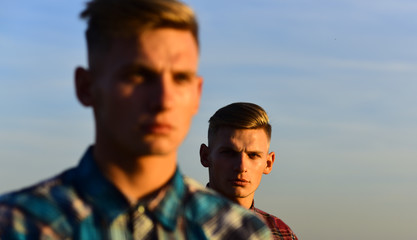 young handsome caucasian twins in shirts look away