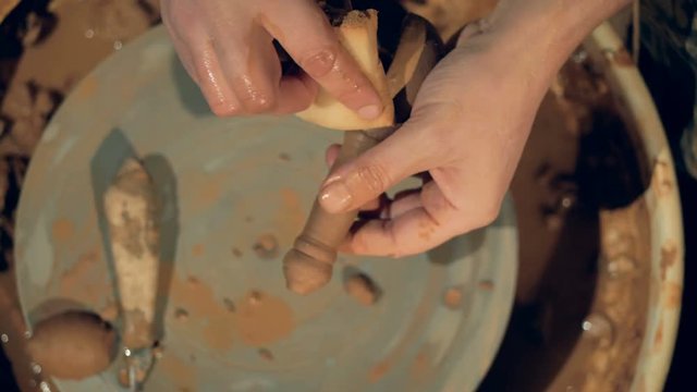 A potter uses a sponge to wet and clean a clay spoon. 