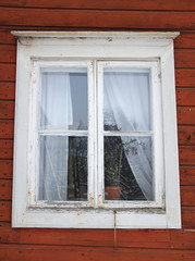 A white window of a red wooden house