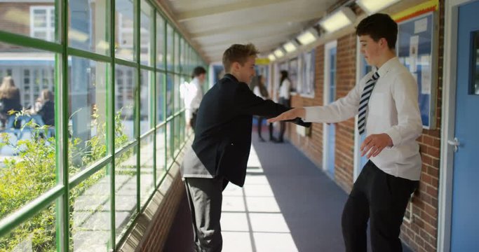 4K School boys greeting each other with elaborate funny handshake in school hallway. Slow motion