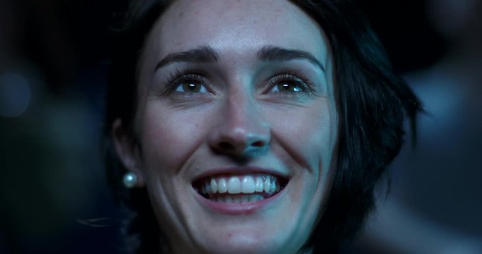 A young woman at the movies begins to smile and laugh
