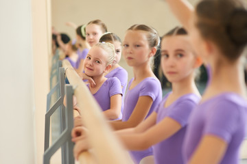 Close up young ballerinas at ballet studio. Young lovely ballet girl near ballet barre. Childrens...