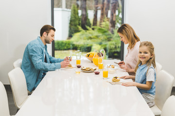 side view of parents and little daughter having breakfast together at home
