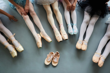 Fototapeta premium Six ballerinas on the floor, top view. Ballet pointe shoes for little ballet girl. Classical ballet school.