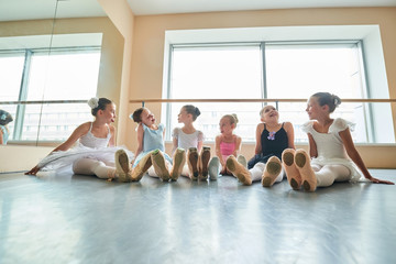 Fototapeta premium Cute ballerinas having fun in studio. Six young ballerinas showing tongues to each other and laughing. They are good friend.