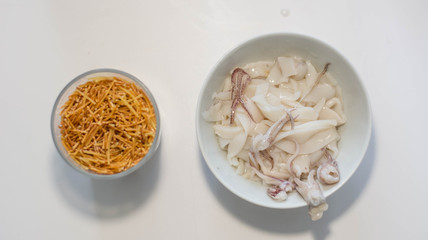 fideua noodles and squid (ingredients for fideua) over a white background, isolated