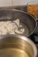 Frying squid in the pan and fideua noodles in a glass, process of making fideua