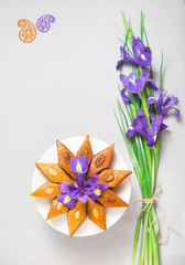 Novruz Azerbaijan spring celebration plate with traditional national sweet pastries pakhlava with walnuts and honey decorated with spring flowers purple fleur de lys on grey background copy space