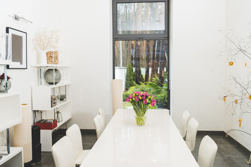 view of stylish empty dining room with bouquet of tulips on table