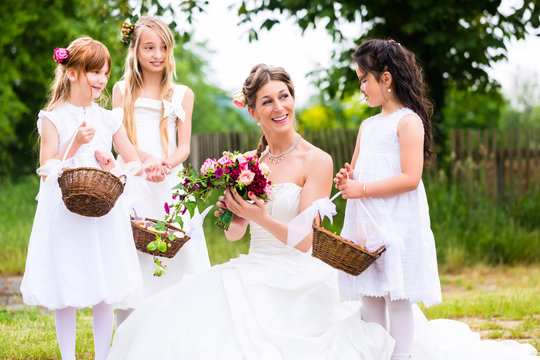 Wedding bride with flower children or bridesmaid outside at garden