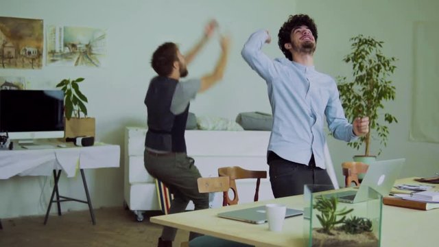 Young men celebrating success in an office.