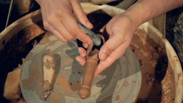 A potter uses a rounded stone to polish inside a clay spoon. 
