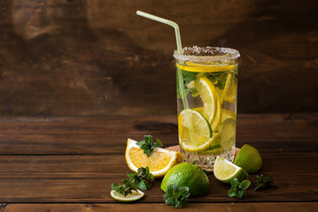 Water with lime, lemon and mint leaves on a dark wooden background