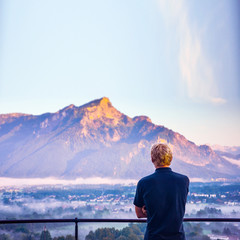Man sitting and thinking in summer morning in Salzburg, Austria. Mountains, Alps in background.