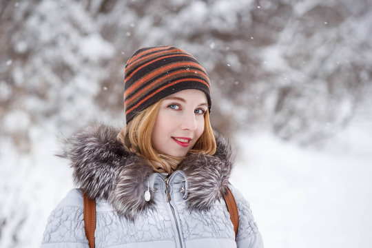 winter portrait of a young beautiful joyful blonde in the snow