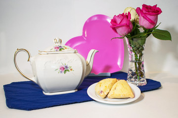 A teapot, pink heart, roses and scones