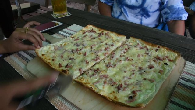 Travelers people cutting pizza thin crust for eat at restaurant in Baden-Württemberg, Germany