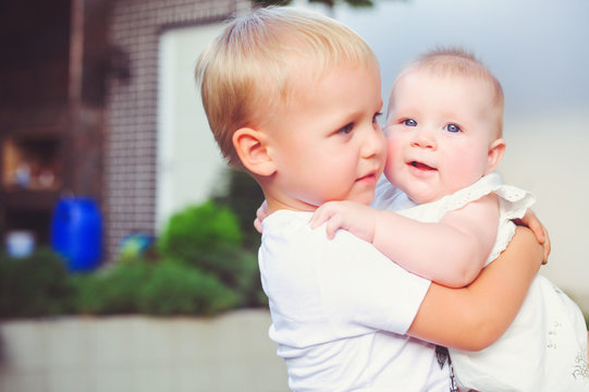 happy little brother playing hugs his sister baby, boy and girl embraces kisses, concept love and parenting