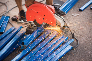 Cut off saw wheel is cutting through a stainless steel square pipe as sparks fly.