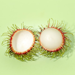 sliced rambutan fruit isolated on green blackground, pop art color concept