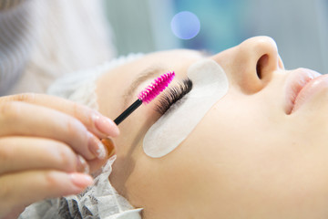 A young girl increases eyelashes in a beauty salon. The process of increasing and volumetric eyelash extensions to a blonde girl.