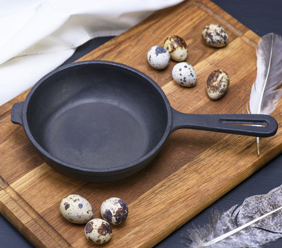 empty black cast-iron frying pan and quail eggs