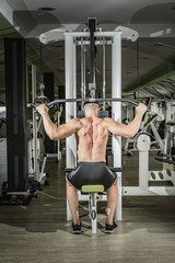 Fototapeta premium Shoulder pull down machine. Fitness man working out lat pulldown training at gym. Upper body strength exercise for the upper back.