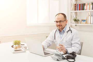 Fototapeta premium Portrait of doctor in glasses sitting at the desktop