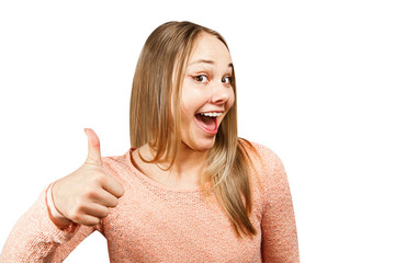 Close up portrait of beautiful smiling young woman in a beige shirt looking forward and showing thumb up, isolated on a white background