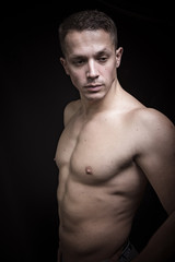 Naklejka premium Portrait of a shirtless athletic guy, black background