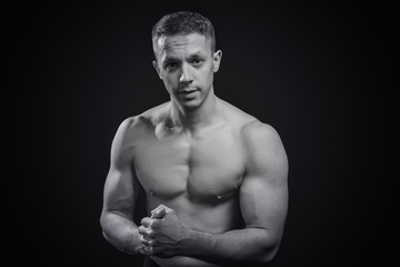 Fototapeta na wymiar Portrait of a shirtless athletic guy, black background