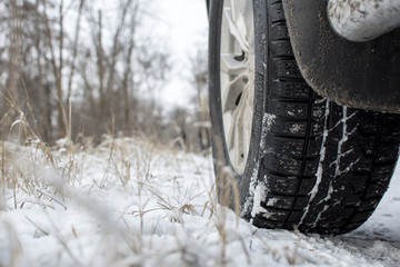 Fototapeta na wymiar foreground wheel of an SUV, on a background of a snowy landscape