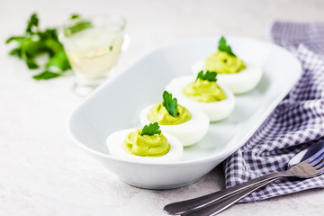 Guacamole devilled eggs with parsley on white background. Selective focus, space for text.