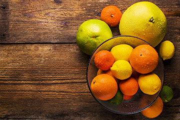 fresh citrus fruits in a glass bowl, top view