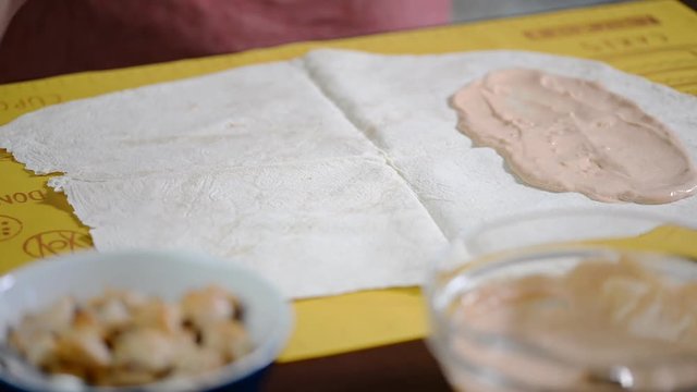 Cook prepares a shawarma. All ingredients on a large pita bread.