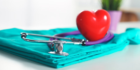 A stethoscope shaping a heart and a clipboard on a medical uniform, closeup