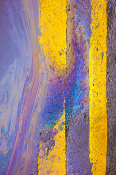 Oil Spill Rainbow Liquid on Yellow Lines on Road