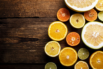 Fototapeta na wymiar colorful citrus fruits, cut in half, on a dark old board