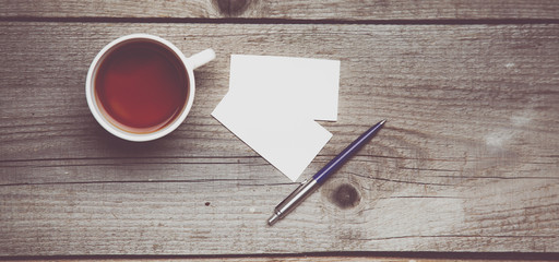 Blank business cards with pen and tea cup on wooden office table