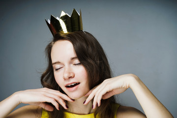 an attractive young girl enjoys, on her head a golden crown, her eyes are closed