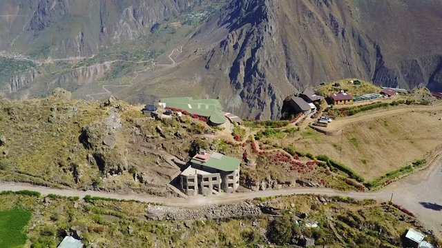 Amazing establishing shot flying over a beautiful house on the edge of a cliff overlooking the Colca Canyon in Peru