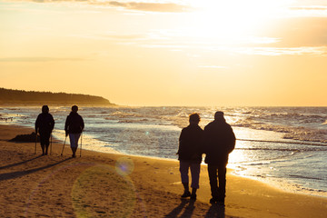 senior couple walk on a beach in sunset