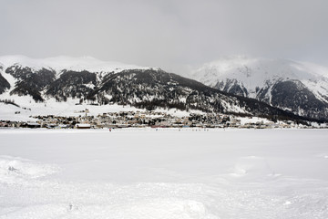 A view of a village in the snow covered landscape and mountains in the alps switzerland