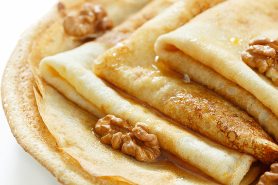 Pancakes with honey and walnuts on a white background