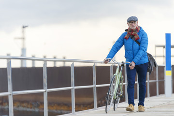 Portrait senior man walking with his bicycle in the street