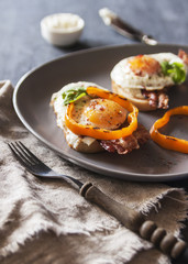 A healthy Breakfast with whole wheat toasts and Poached egg with green salad, bacon and pepper. Rustic style on dark background. Selective focus. Vertical.
