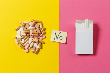 Medication white colorful round tablets arranged abstract white pack of cigarettes on yellow color...