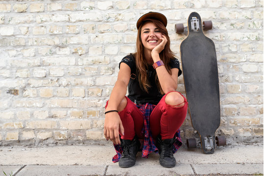 Cute trendy urban girl with longboard outdoors